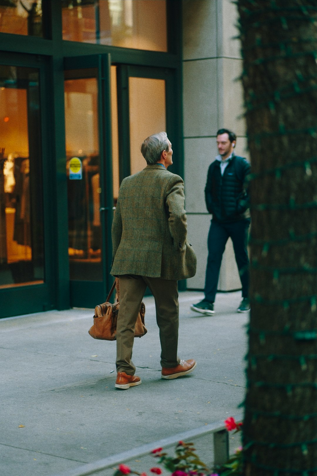 man-in-tweed-jacket-walks-past-store-entrance-voms8r-nnp0